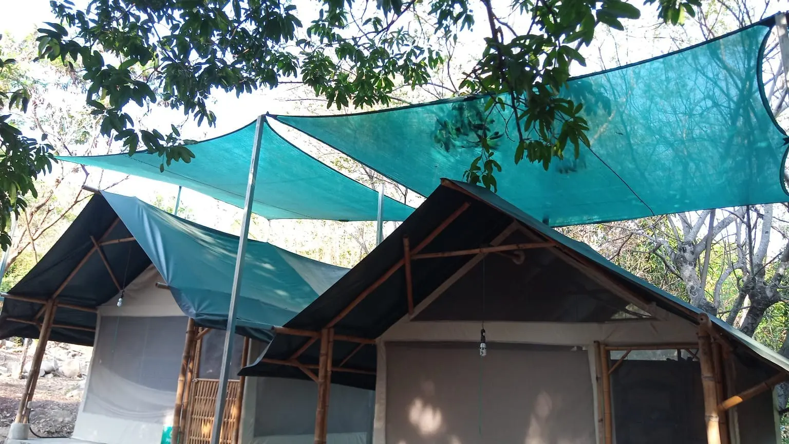 Velarias de malla sombra color turquesa tensadas sobre dos cabañas