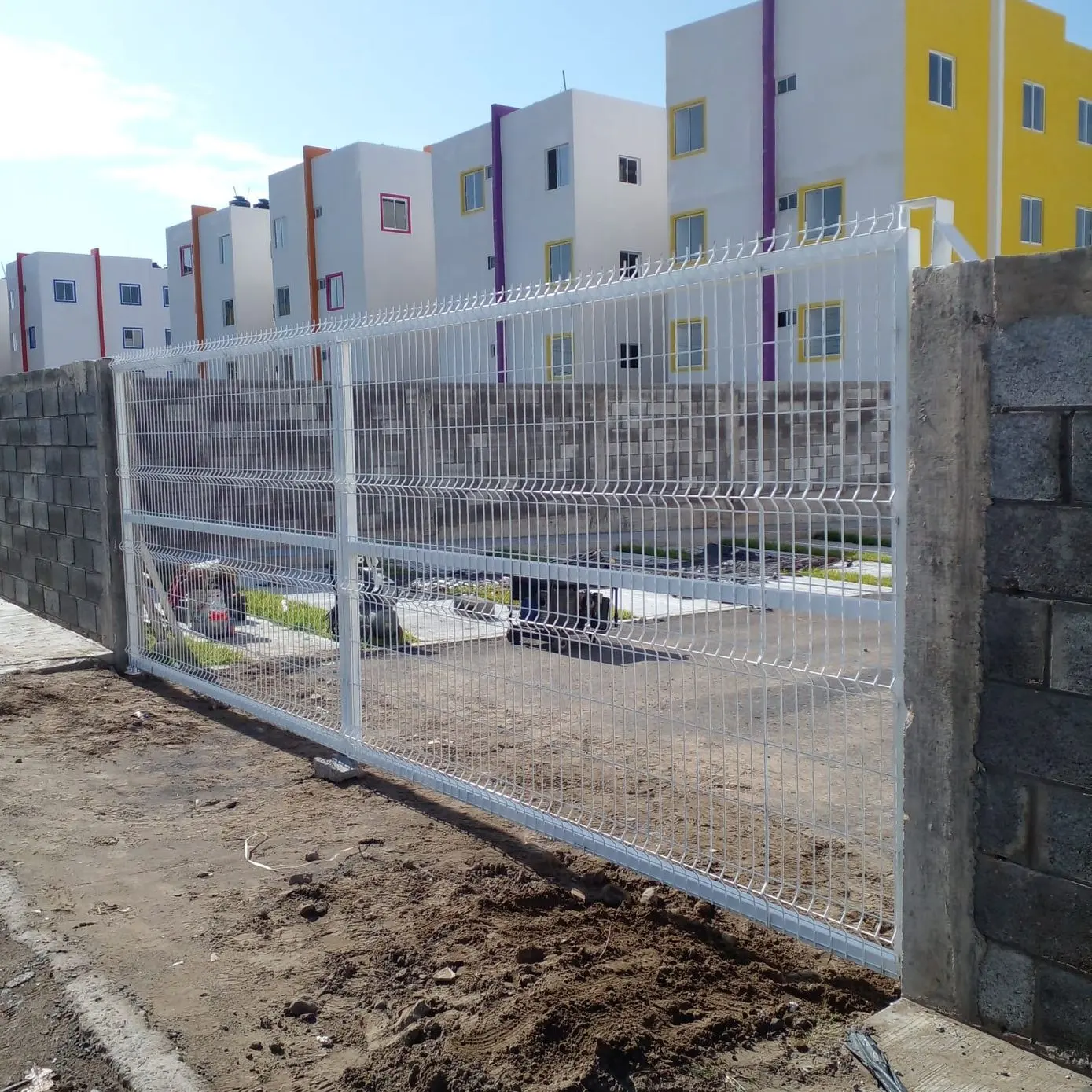 Reja de acero galvanizada blanca instalada entre columnas de block frente a un fraccionamiento